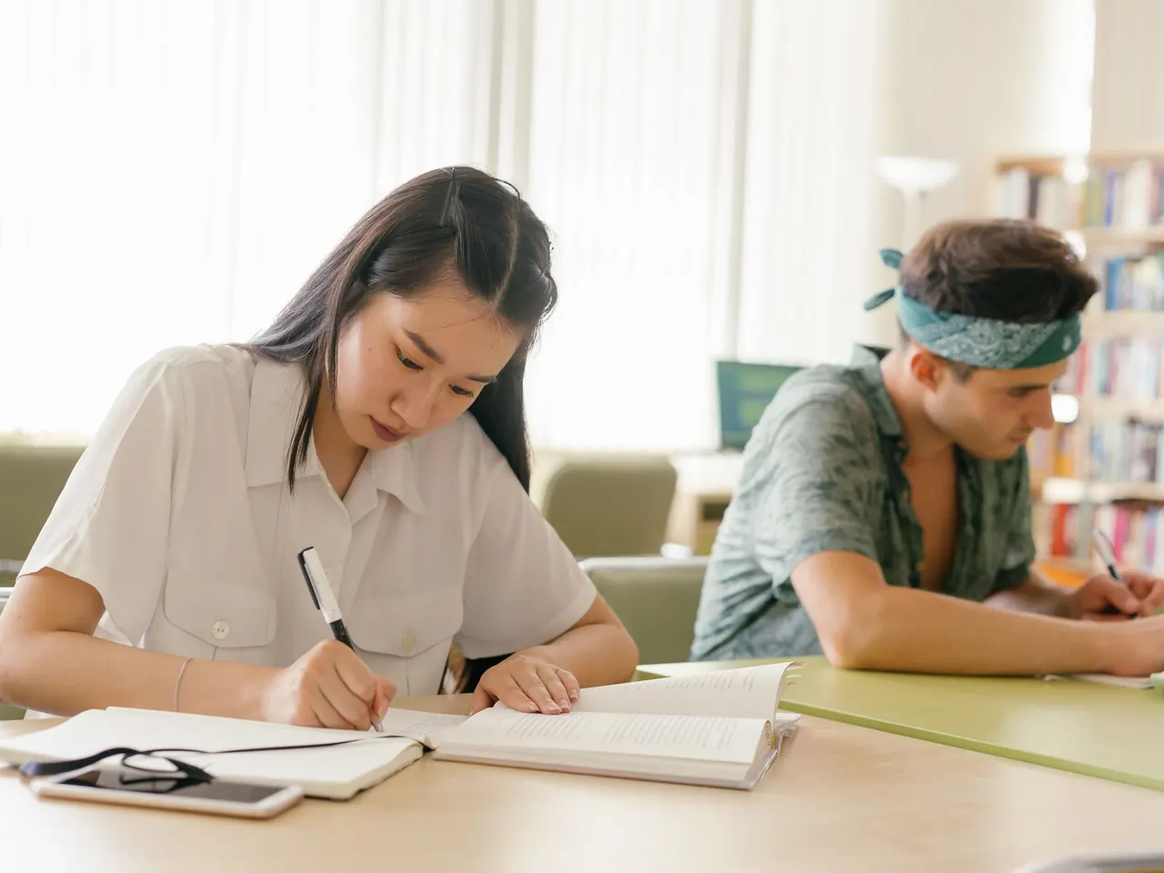 Two students working through written questions side by side at a study table